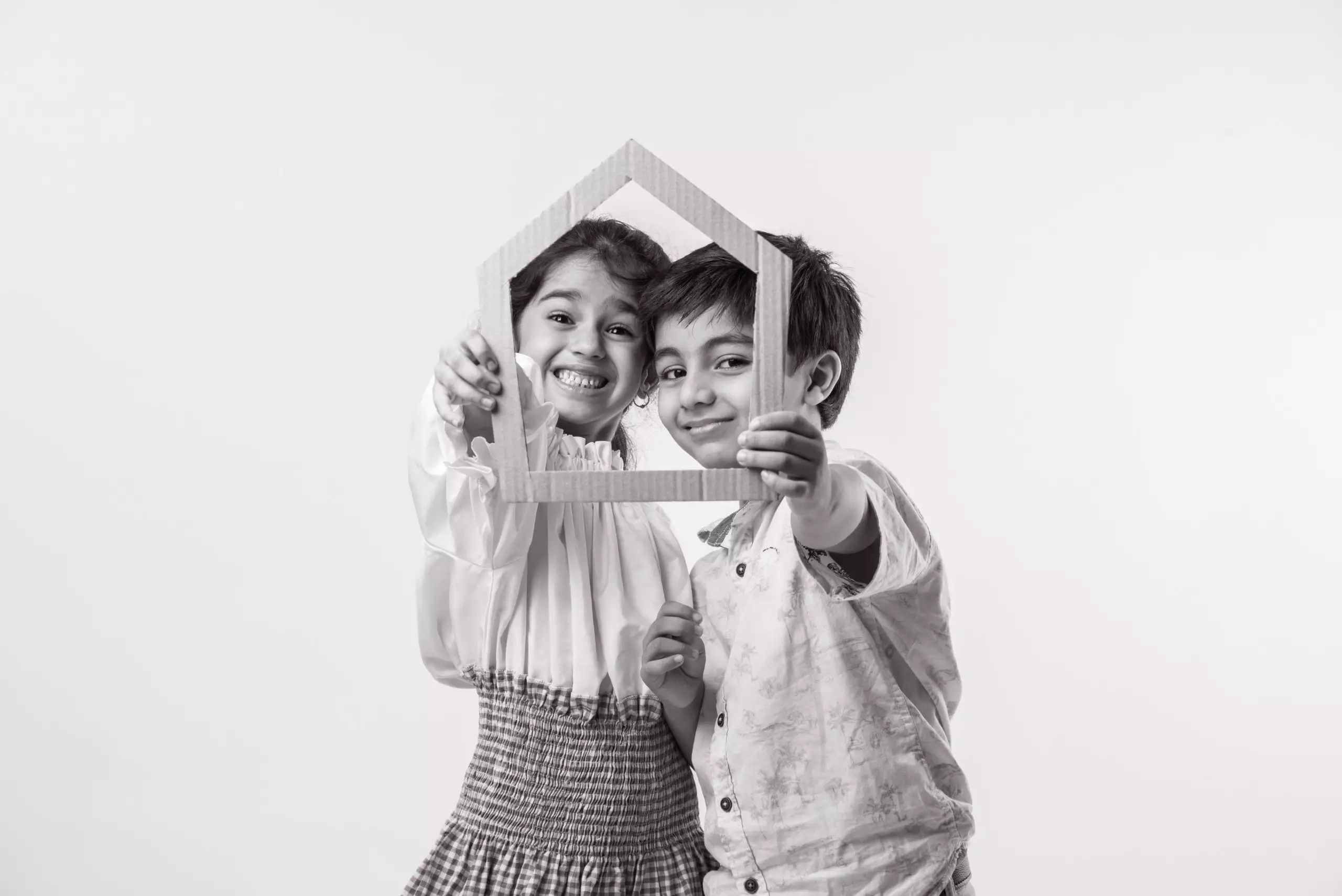 Indian kids holding 3D paper house model - showing Craft or real estate concept